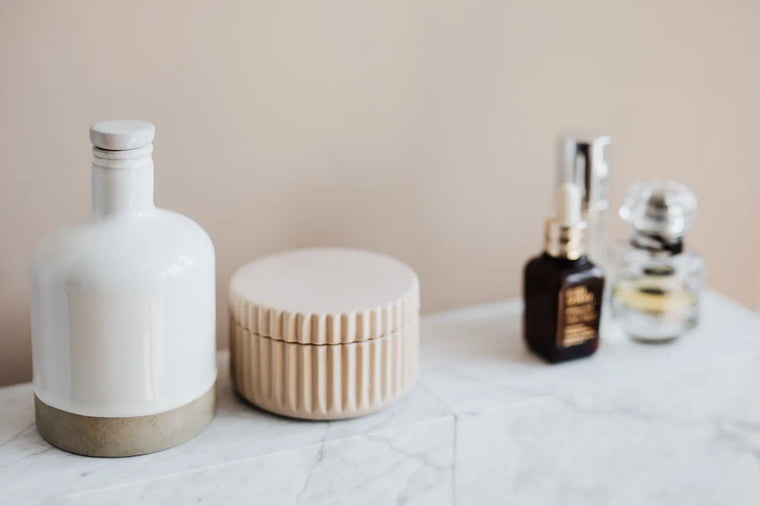 Unbranded cream jar with botanicals on linen, warm neutral moisturizer still life.