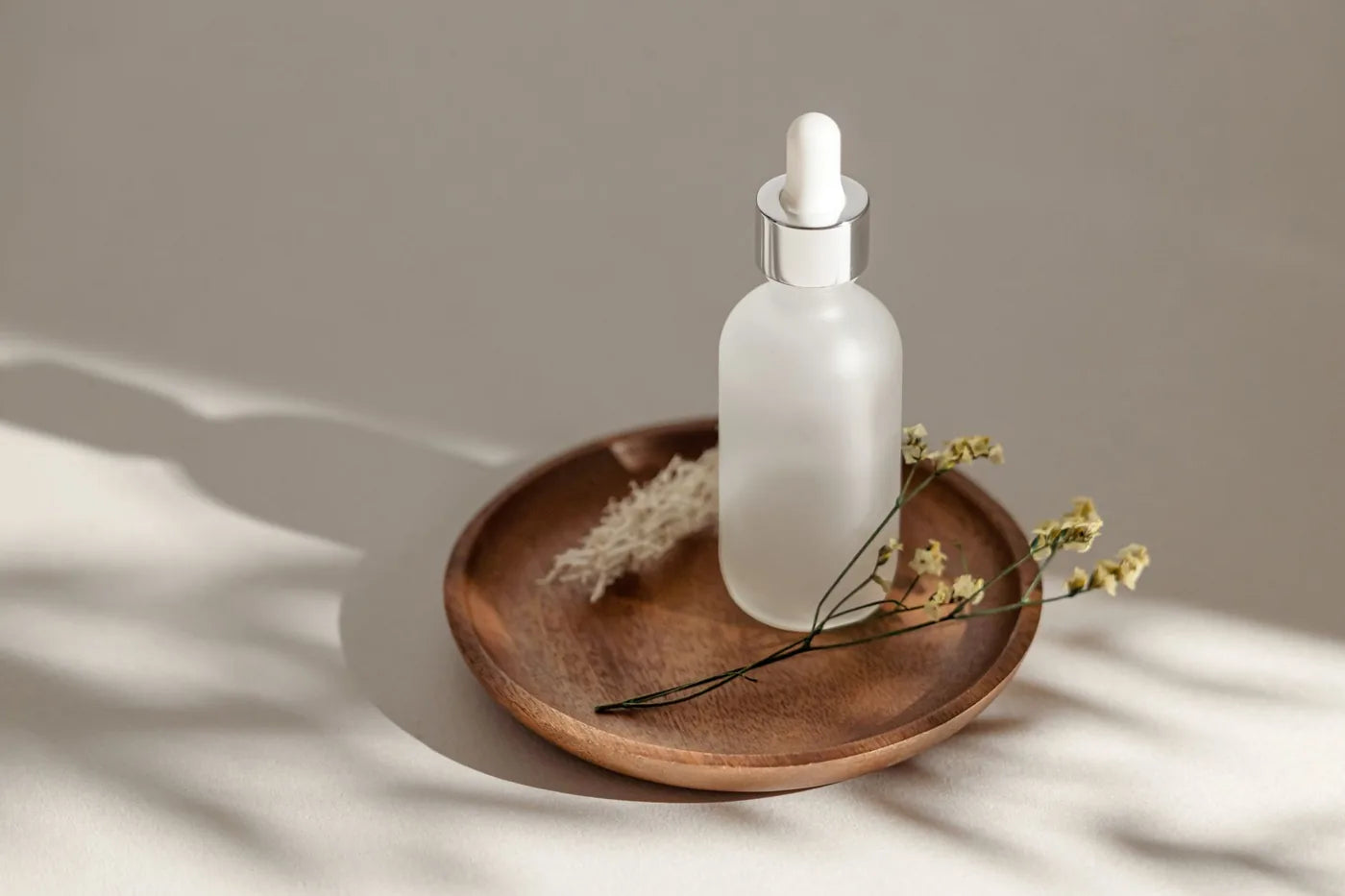Frosted glass serum bottle in soft neutral light, water-free skincare formulation.
