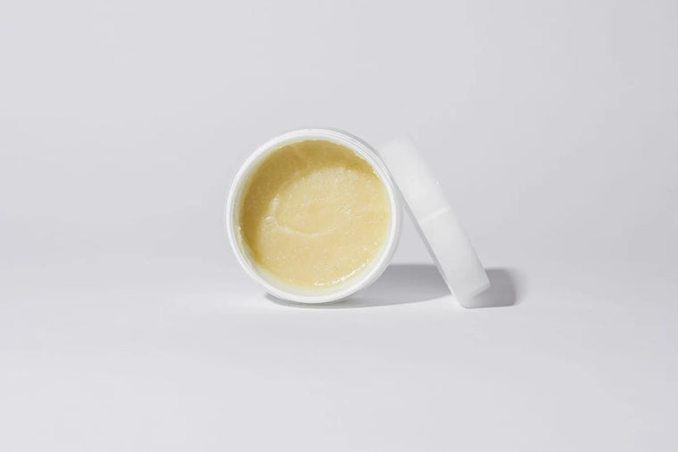 Natural balm in an open jar on linen, warm neutral still life.