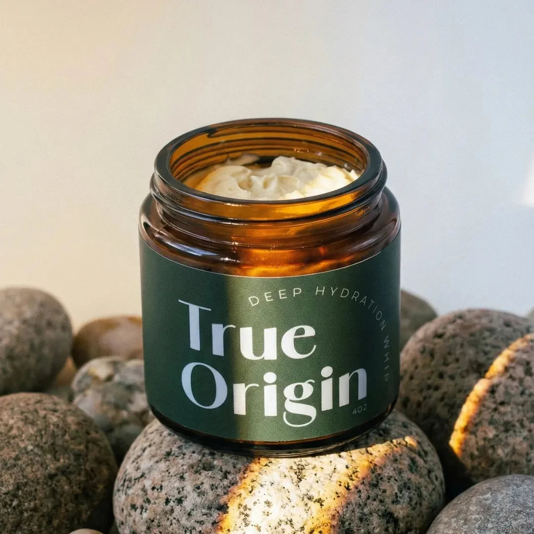 True Origin Deep Hydration Whip jar on river stones