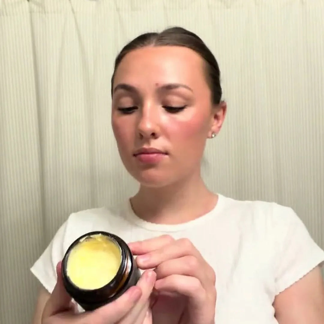 Woman holding an open Deep Hydration Whip jar showing the whipped tallow texture before applying